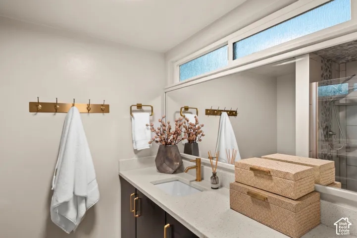 Built-in vanity with a single sink, light-toned countertop, dark wood-finish cabinetry, and gold-finish hardware