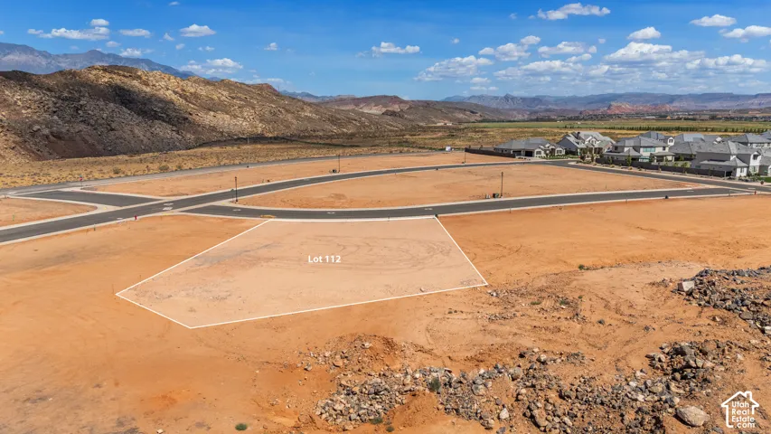 Expansive lot with flat topography, surrounded by paved roads and established infrastructure, featuring distant mountain scenery