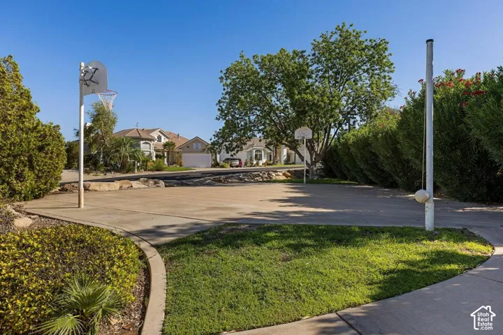Hardscaped recreation court with two basketball hoops, bordered by manicured greenery and mature trees