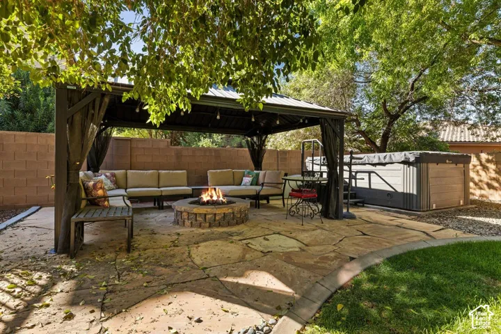 Expansive flagstone patio featuring a built-in fire pit, a covered gazebo, and an outdoor spa