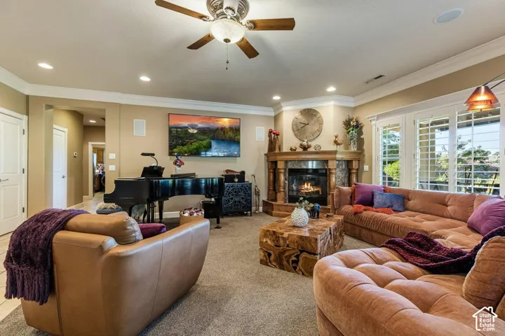 Living area featuring a corner fireplace with a wood mantle, built-in recessed lighting, a ceiling fan with light, and plantation shutters