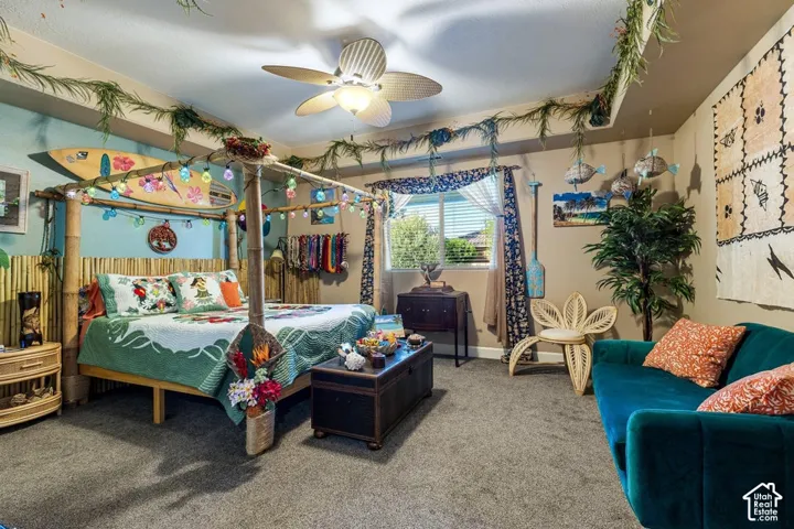 Carpeted bedroom featuring a built-in bamboo bed frame, ceiling fan with integrated lighting, and a window with blinds