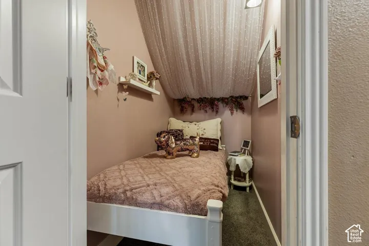 Angled ceiling with a soft pink finish, recessed lighting, and dark gray carpet flooring