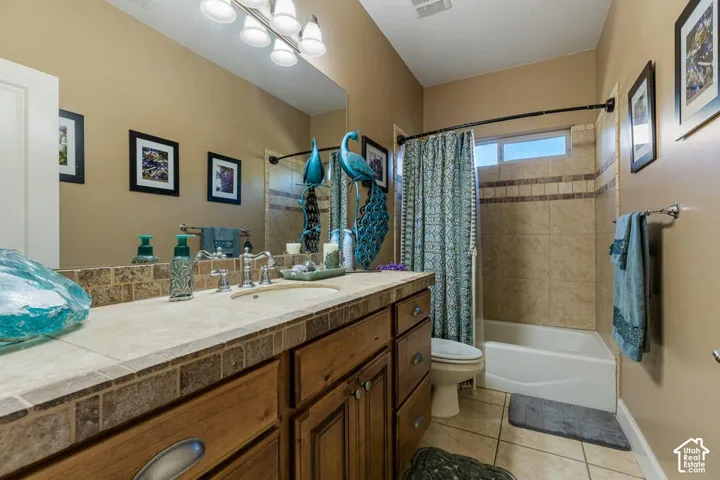 Vanity with wood-finish cabinetry, tile countertop, and a full-width mirror