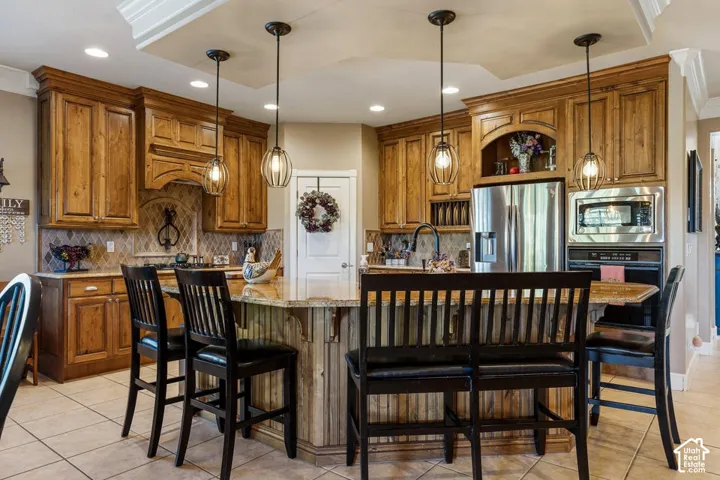 Custom cabinetry, stainless steel appliances, recessed lighting, tile flooring, and a multi-level island with seating