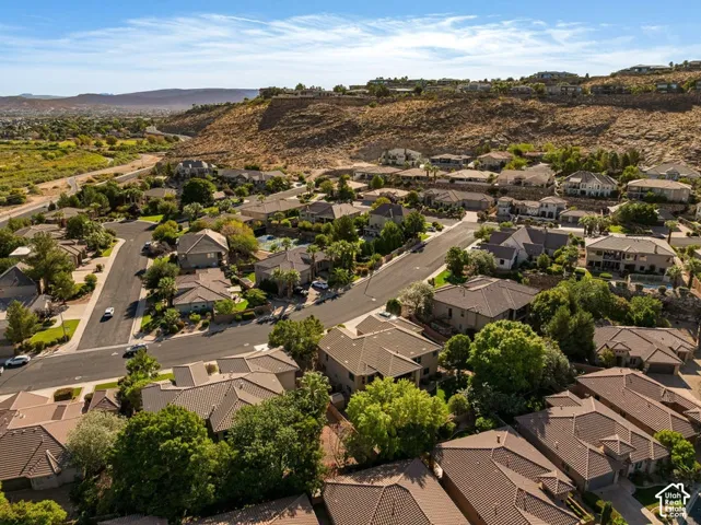 Residential properties with varied architectural styles, mature landscaping, and paved roadways, set against a mountainous backdrop