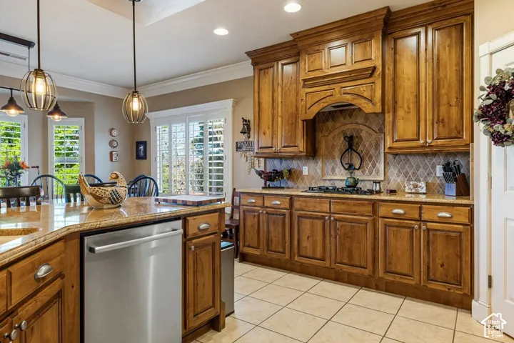 Custom wood cabinetry with an integrated range hood, tile backsplash with decorative inset, granite countertops, and stainless steel appliances