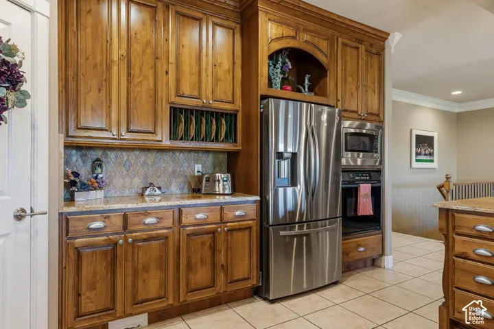 Wood cabinetry with a natural finish, stainless steel refrigerator, built-in microwave, integrated oven, and granite countertops