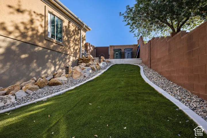 Artificial turf yard with concrete curbing, rock landscaping, and a block wall perimeter