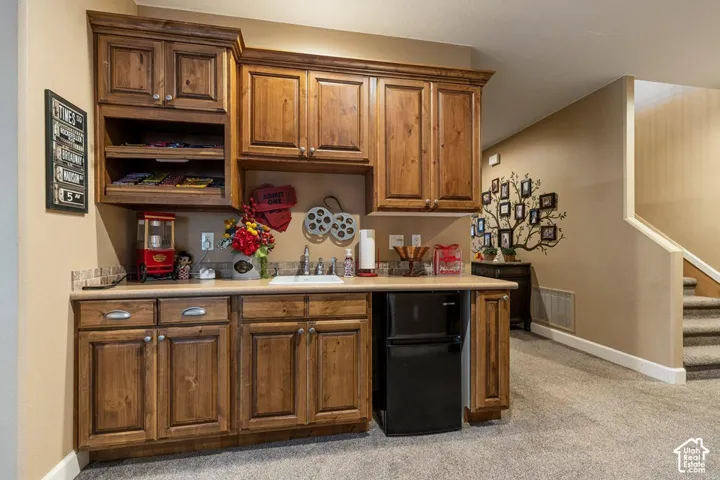 Built-in cabinetry with wood-finish doors and drawers, under-cabinet lighting, a countertop, and a built-in sink