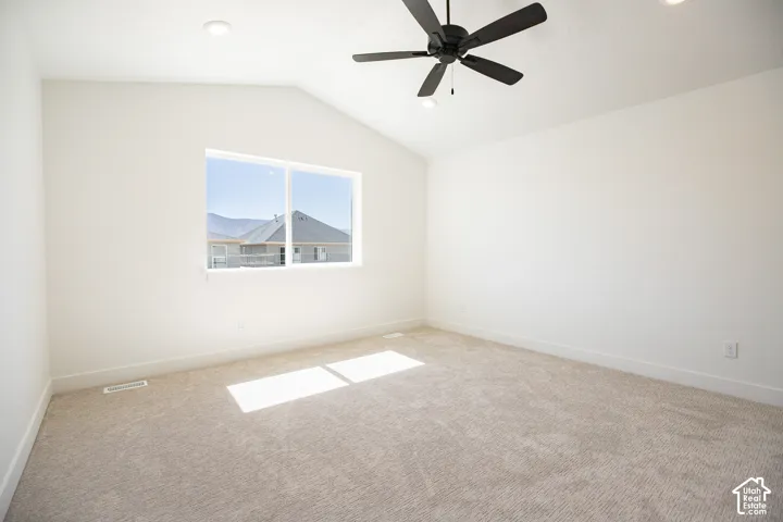 Primary bedroom with vaulted ceiling, ceiling fan and walk-in closet as part or primary suite.