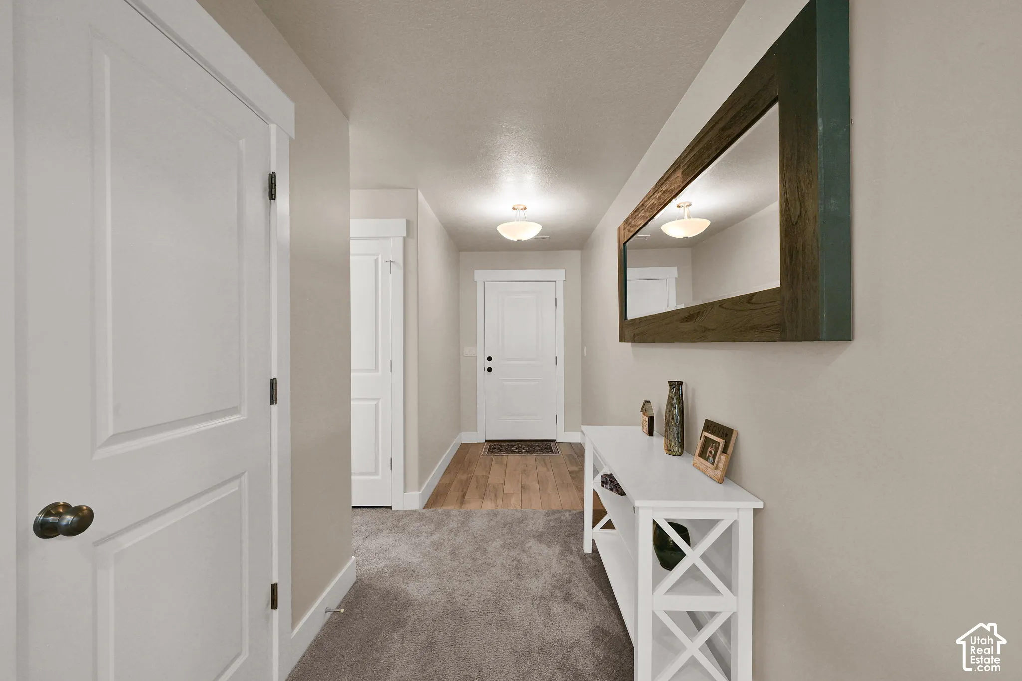 Recessed lighting illuminates the hallway with plush carpeting and wood-finish flooring