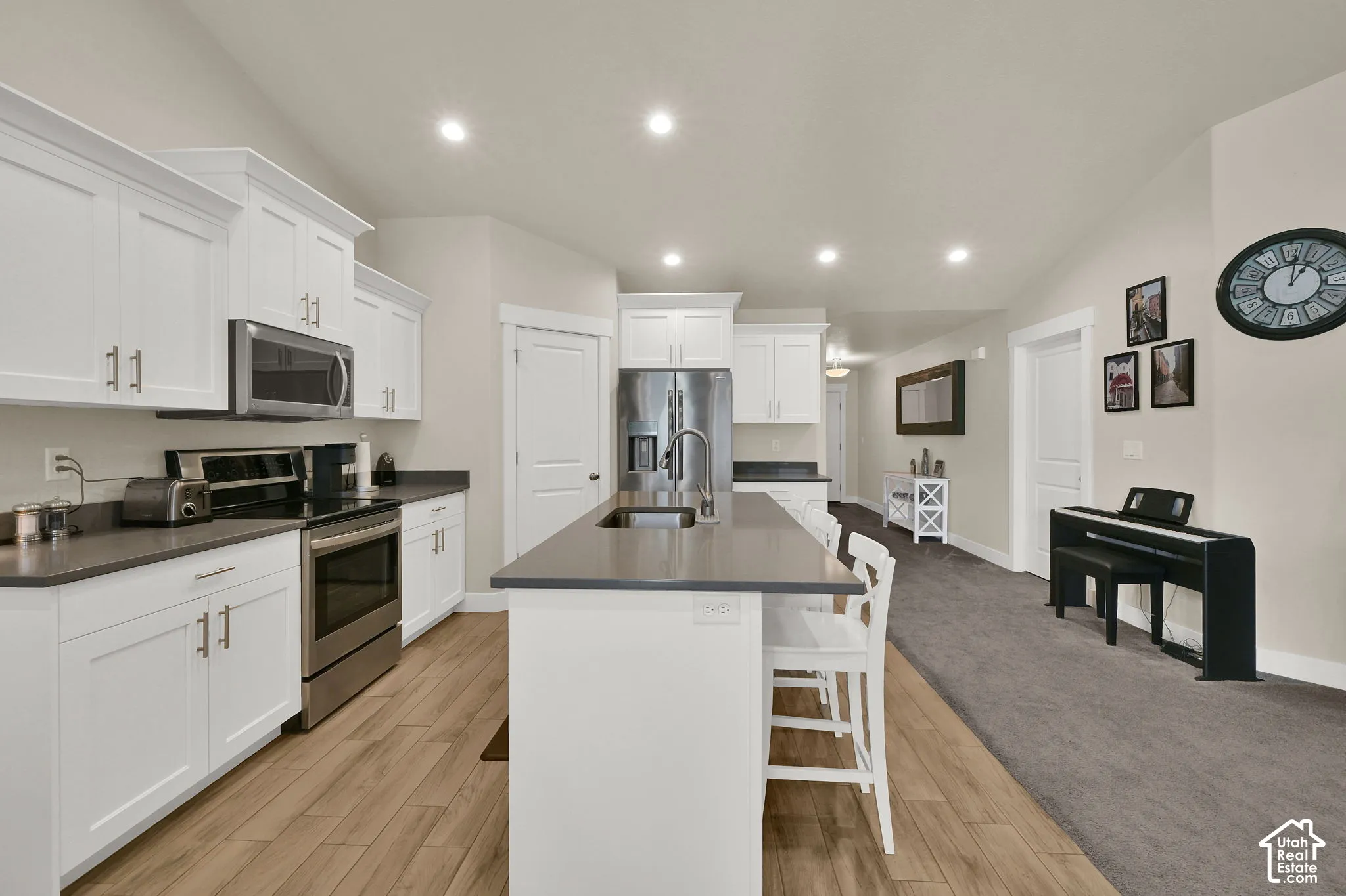 Kitchen with white cabinetry, stainless steel appliances, and a central island with countertop seating