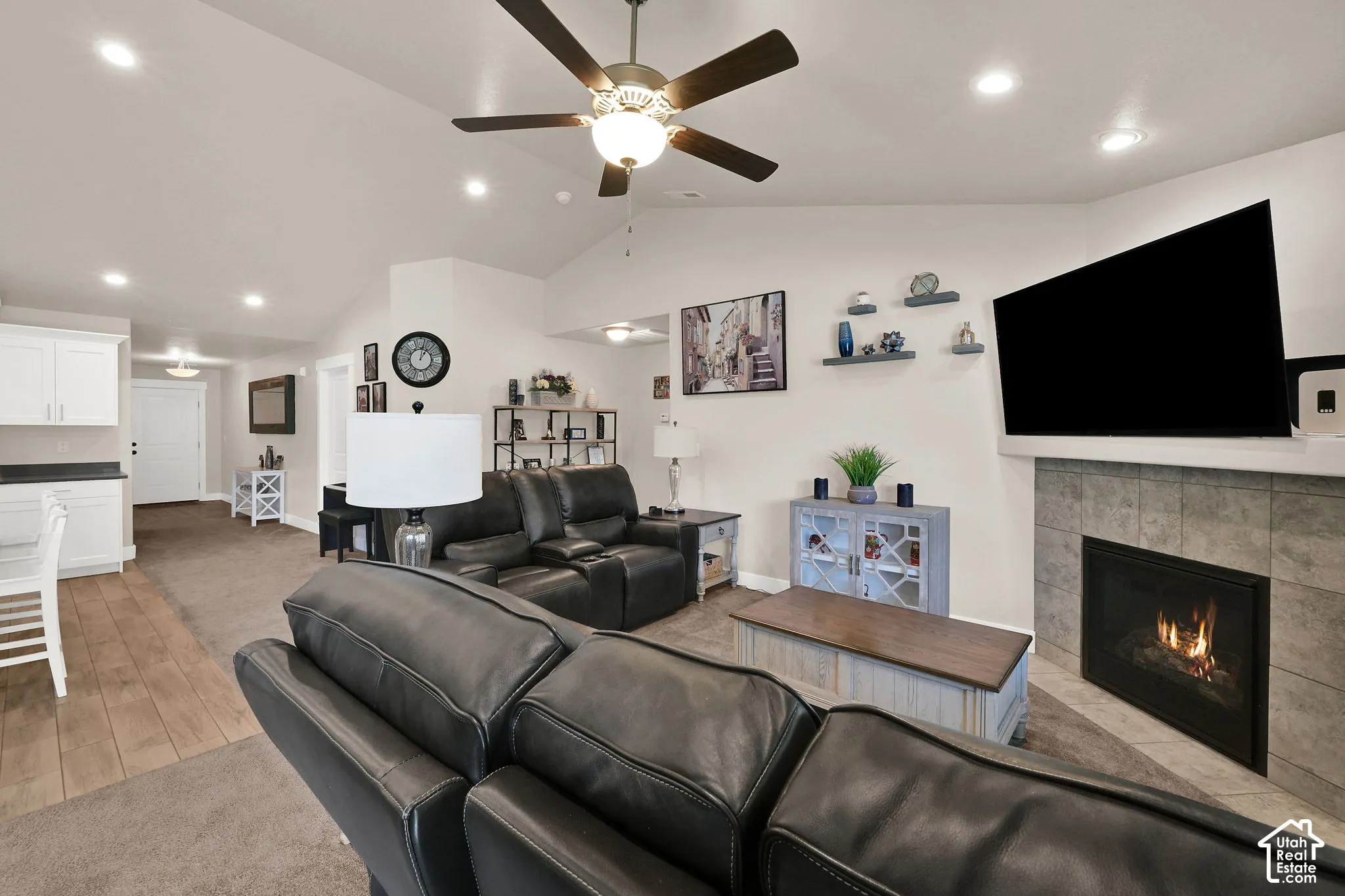 Vaulted ceiling with a ceiling fan, recessed lighting, and a tiled fireplace