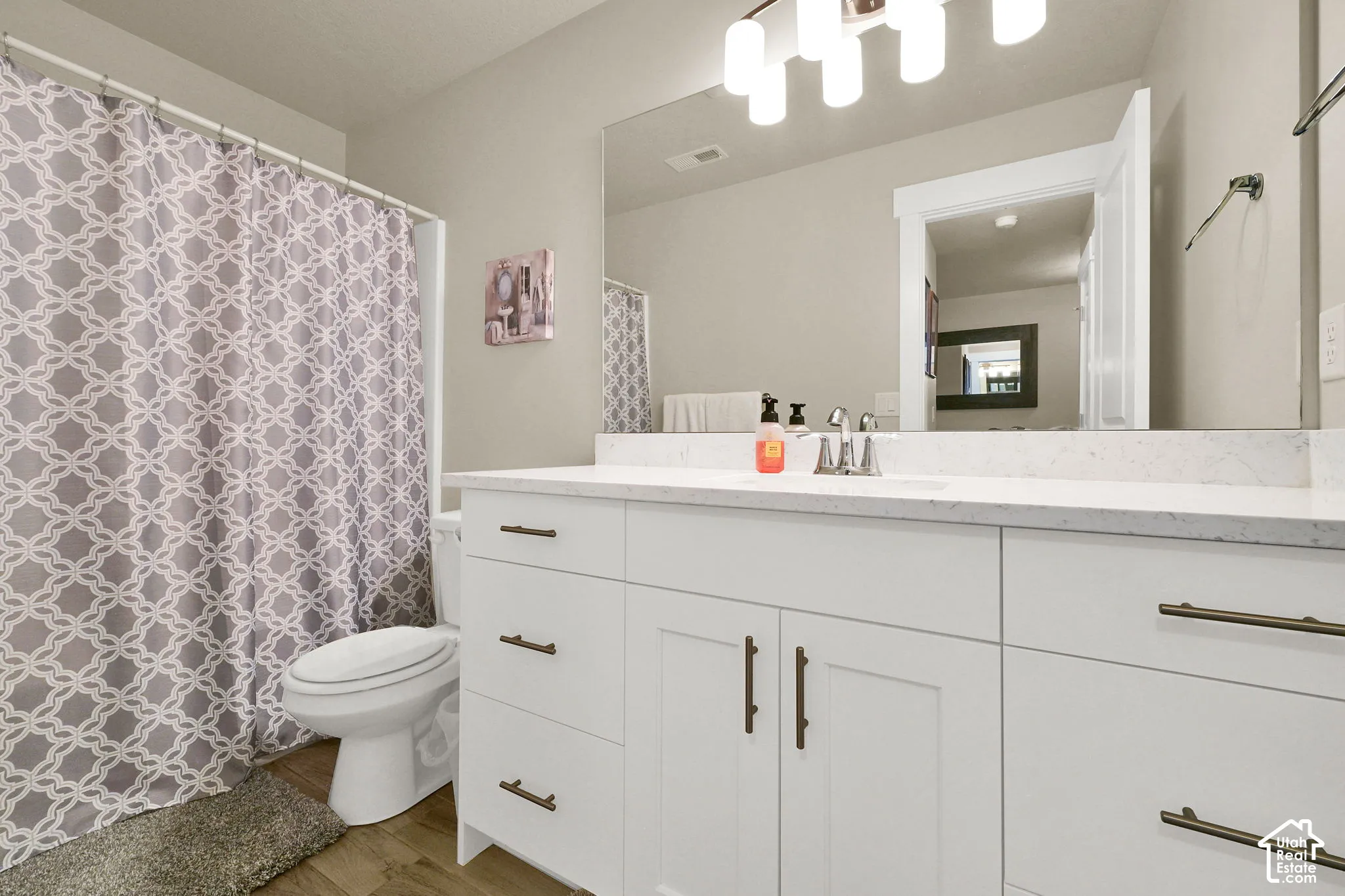 White vanity with multiple storage drawers and cabinet doors, large mirror, and a white countertop