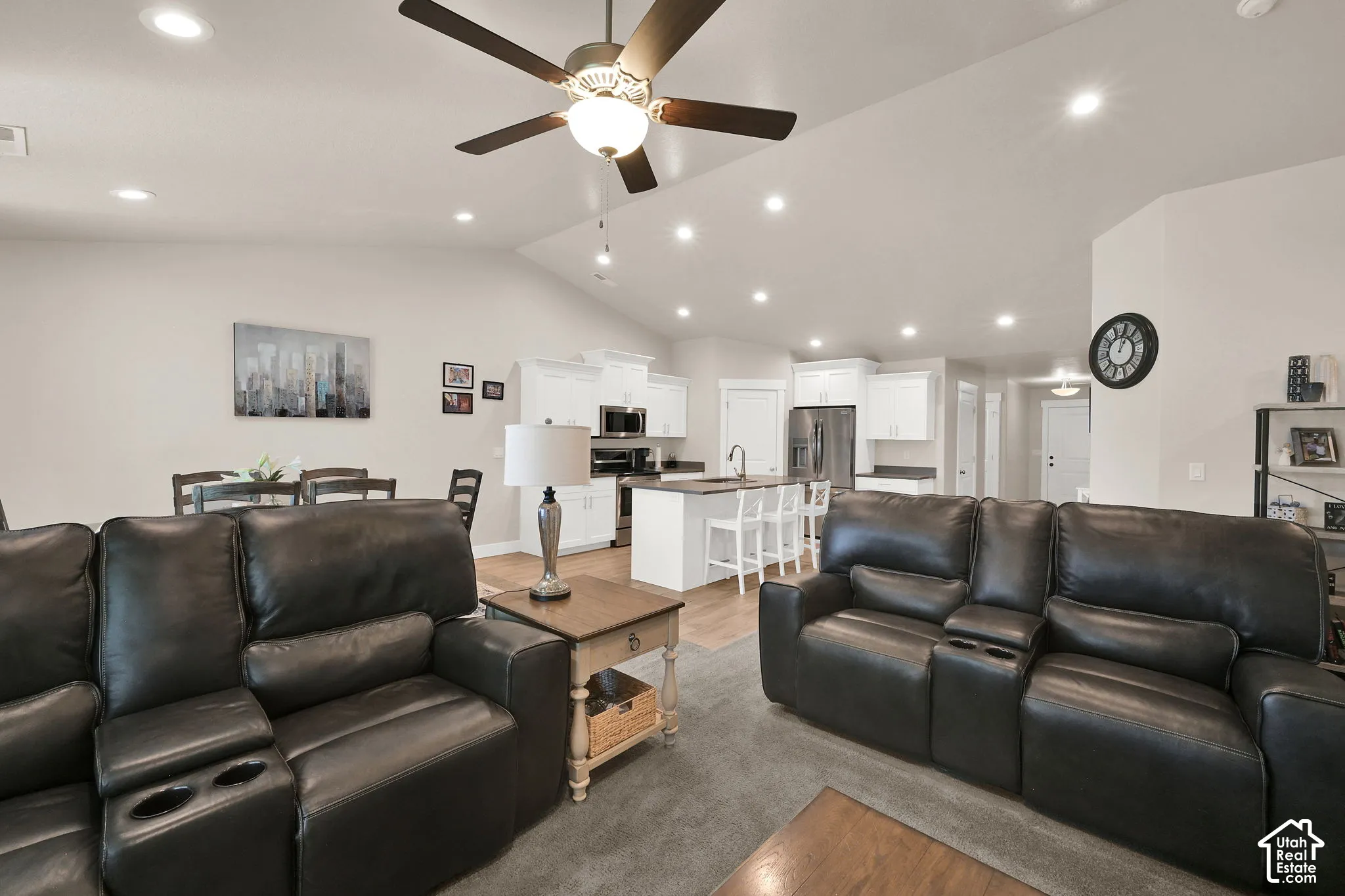 Vaulted ceiling with recessed lighting and a ceiling fan, wood-finish flooring, white cabinetry, and stainless steel appliances
