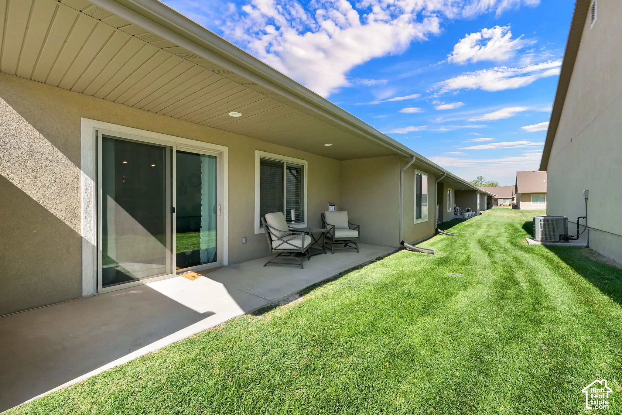 Covered concrete patio with stucco exterior, sliding glass door, and adjacent window