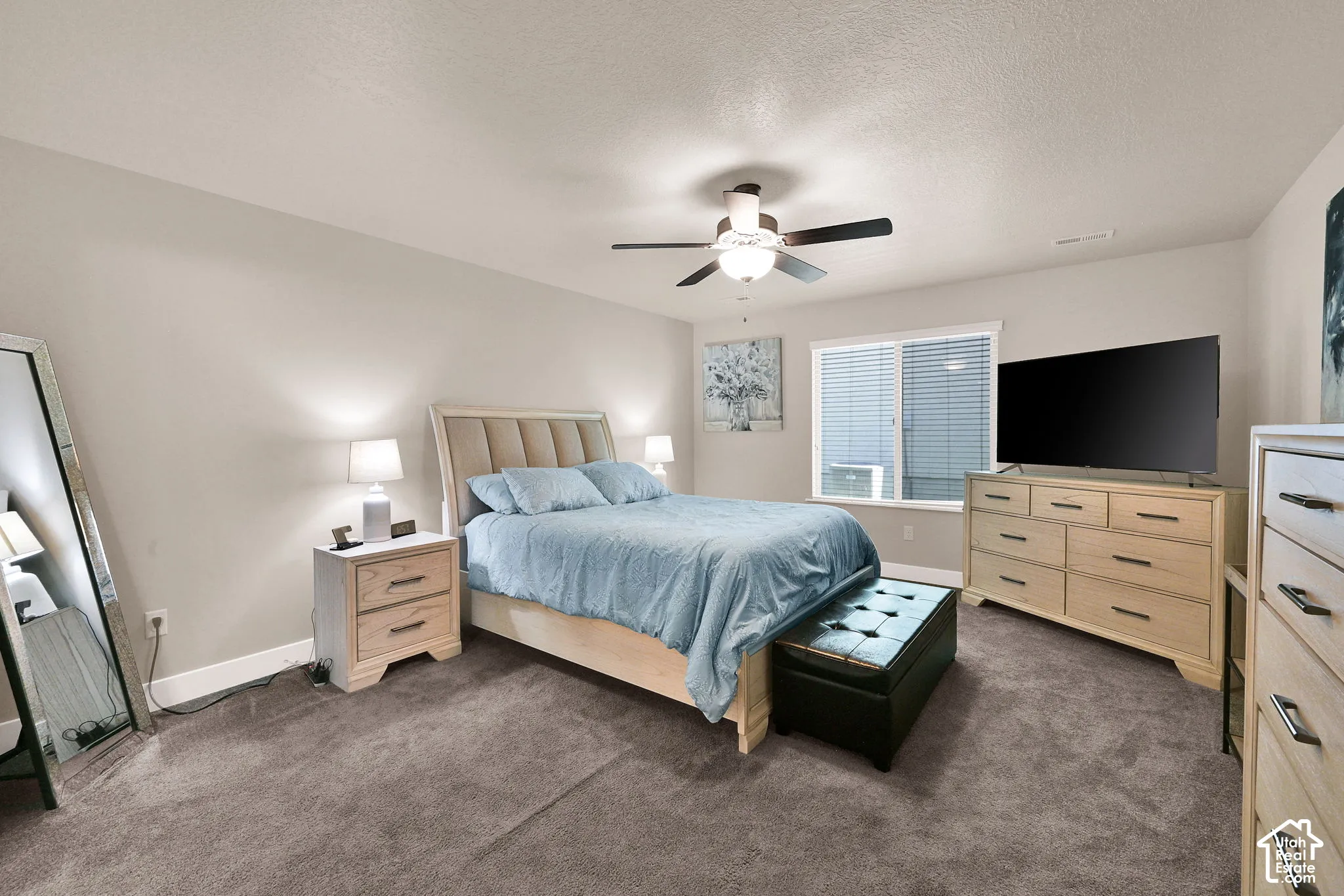 Neutral wall paint, textured carpeting, a ceiling fan, and a window with blinds