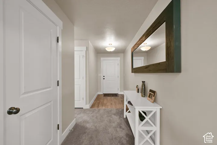 Recessed lighting illuminates the hallway with plush carpeting and wood-finish flooring