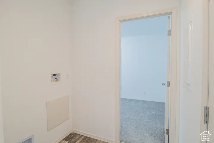 Utility area featuring wood-finish flooring and a white wall-mounted electrical panel