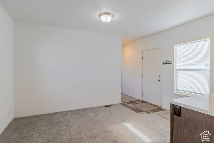 Recessed lighting, window with blinds, wood-finish cabinetry, light-toned countertop, and light-toned carpet flooring