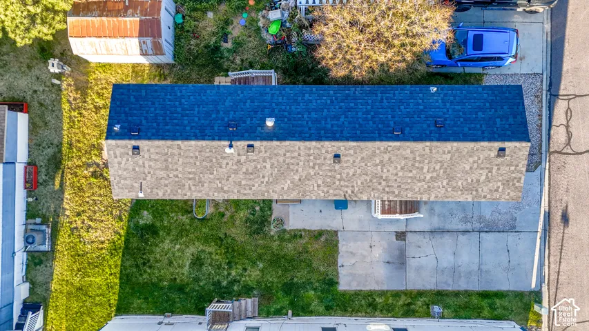 Asphalt shingle roof with multiple vents, adjacent to a paved driveway and grassy areas