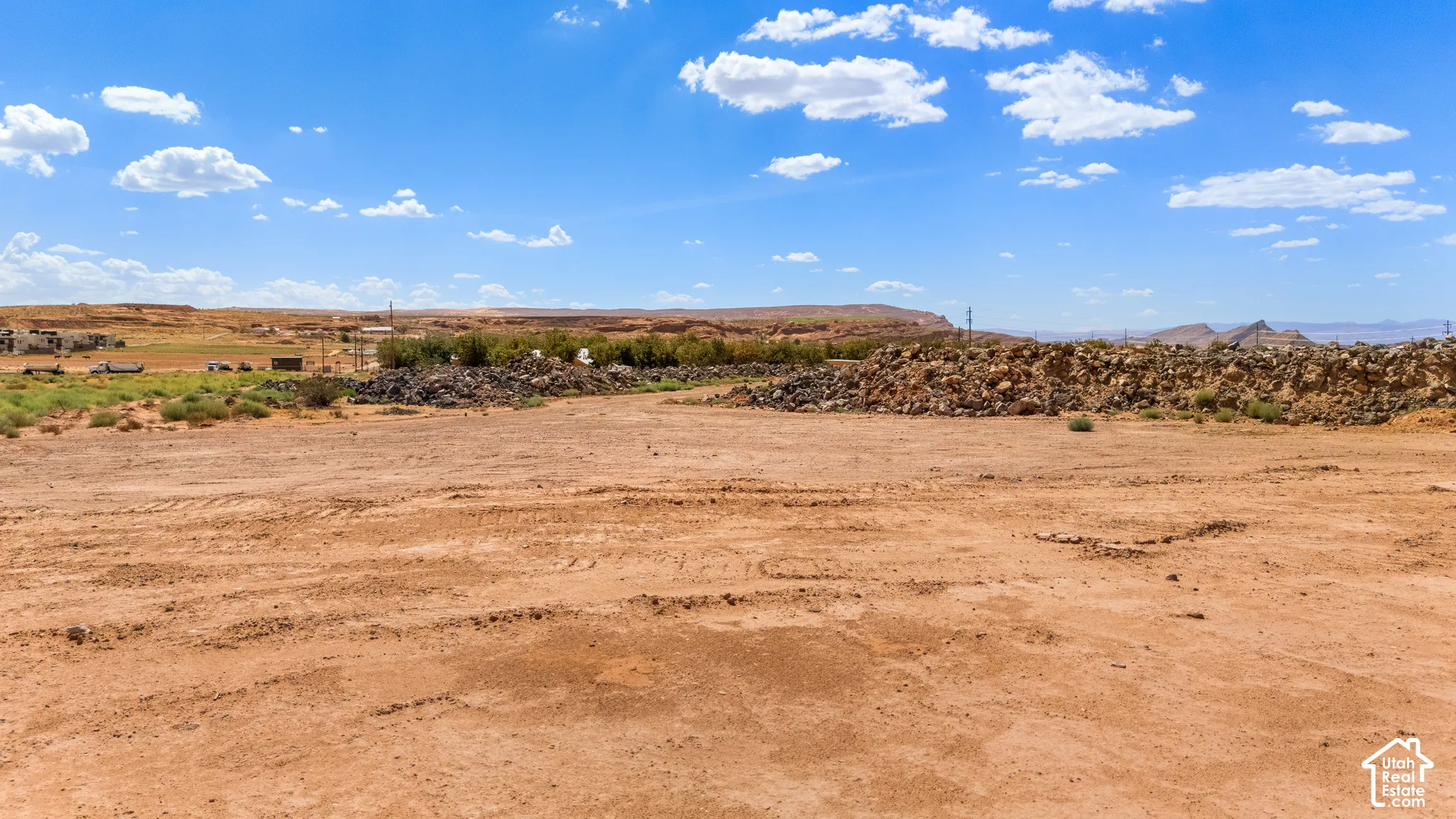 Expansive arid land featuring a dirt surface and distant rolling hills