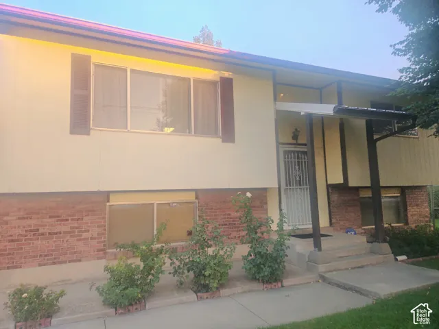 Brick and siding exterior with a covered entry, security screen door, and multiple windows