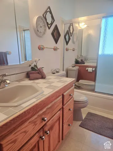 Wood-finish vanity with chrome hardware, tiled countertop, and integrated sink