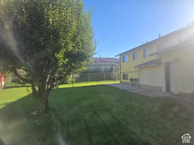 Expansive lawn with mature foliage, patio area, and a light-toned exterior