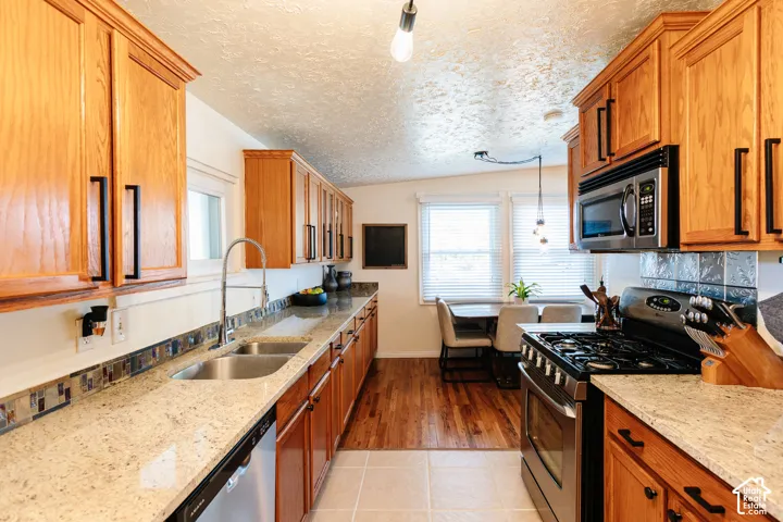 Kitchen featuring wood cabinetry, stone-finish countertops, stainless steel appliances, and a mosaic tile backsplash