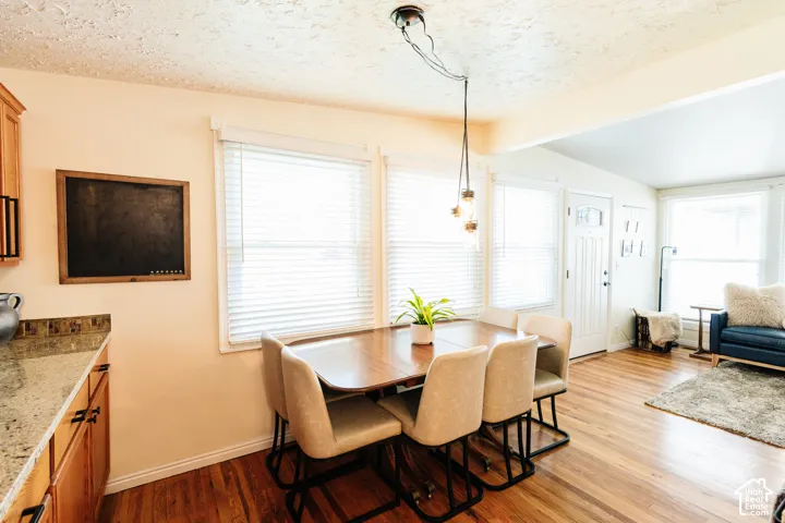Hardwood flooring throughout, multiple windows with blinds, recessed lighting, wood cabinetry, and a granite-finish countertop