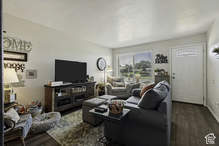 Wood-finish flooring, white paneled door with decorative glass insert, multi-pane window with blinds, and a built-in media console