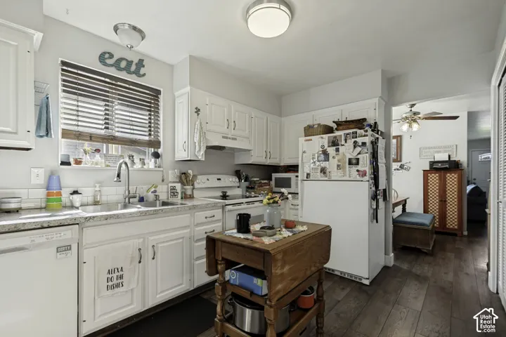 White cabinetry with ample storage, white appliances, wood-finish flooring, and a kitchen sink with a window