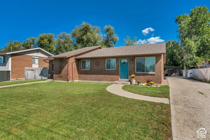 Brick exterior home with a light-colored shingle roof, a vibrant blue entry door, and a concrete driveway