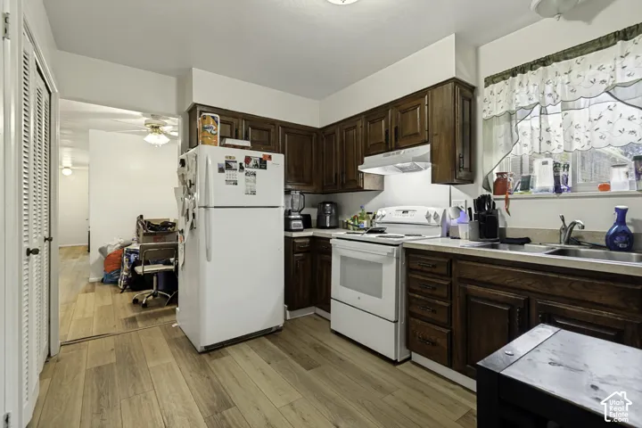 Kitchen featuring wood-finish flooring, dark wood cabinetry, white appliances, and a double basin sink