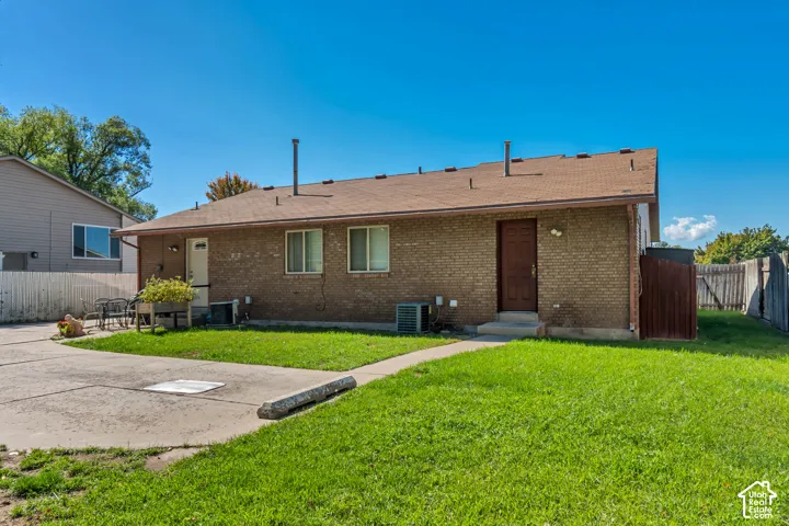 Brick exterior with multiple windows, a brown shingled roof, and a concrete pathway