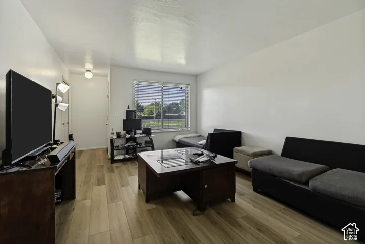 Expansive interior featuring wood-finish flooring, white walls, and a large window with horizontal blinds