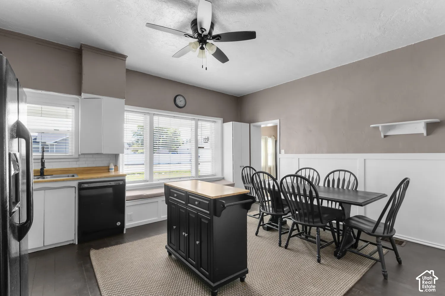 Kitchen and dining area featuring white cabinetry, a white subway tile backsplash, a wood-finish countertop, dark appliances, and a built-in window seat
