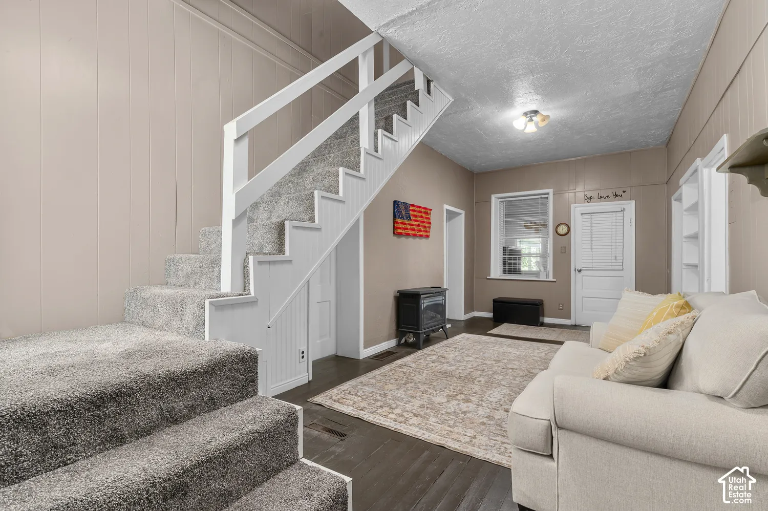 Carpeted staircase with white risers, dark wood-finish flooring, paneled walls, built-in shelving, and a prominent window