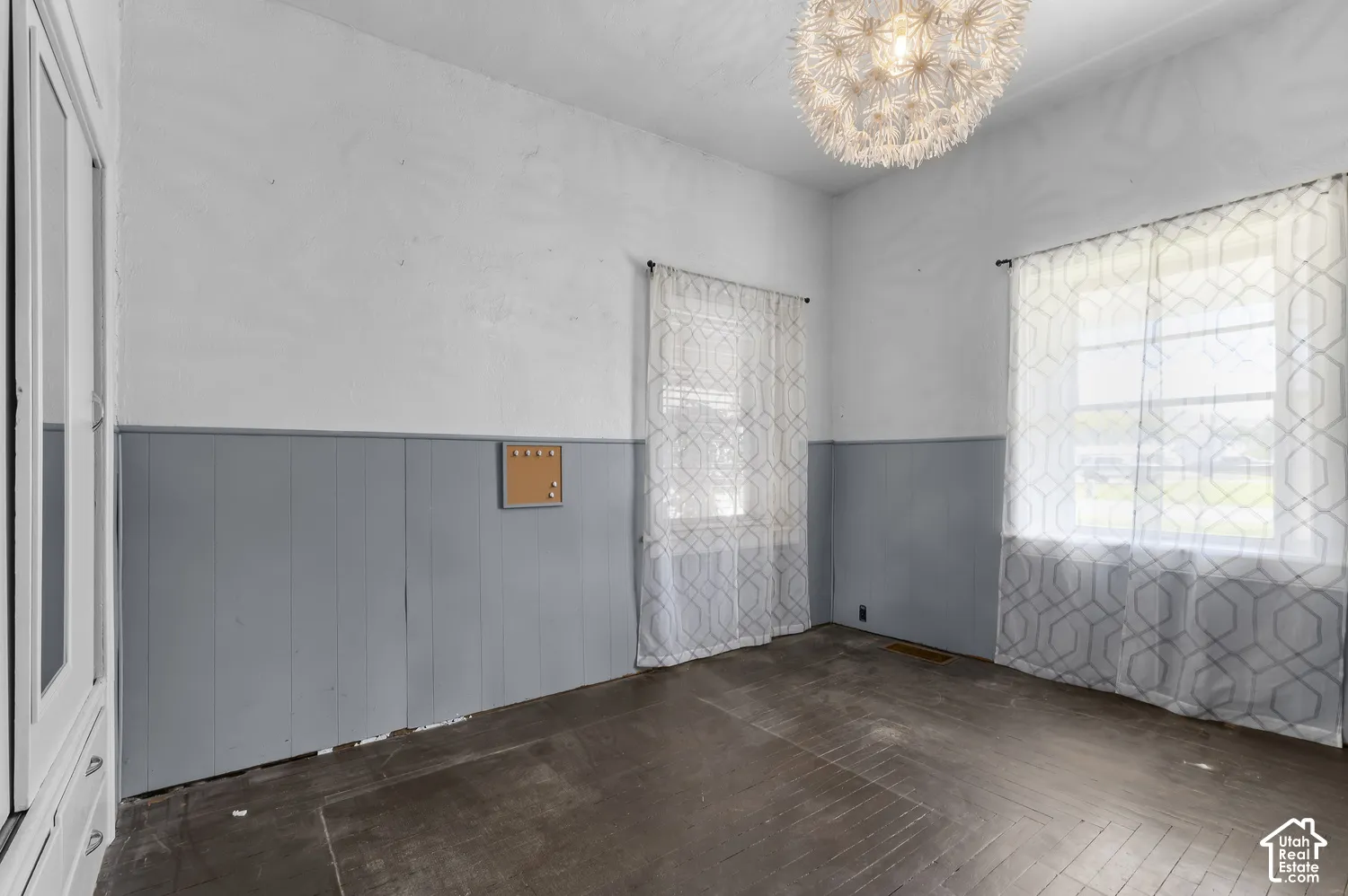 Wood-finish flooring, two large windows, built-in cabinetry, and a unique overhead light fixture
