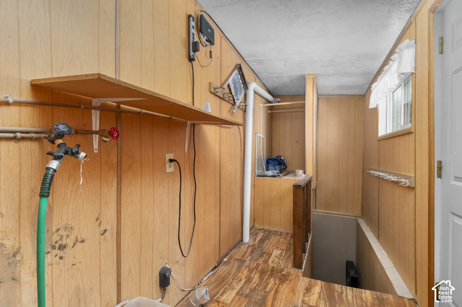 Wood paneling throughout, built-in shelving, white trim window, built-in clothing rod, and wood-finish flooring