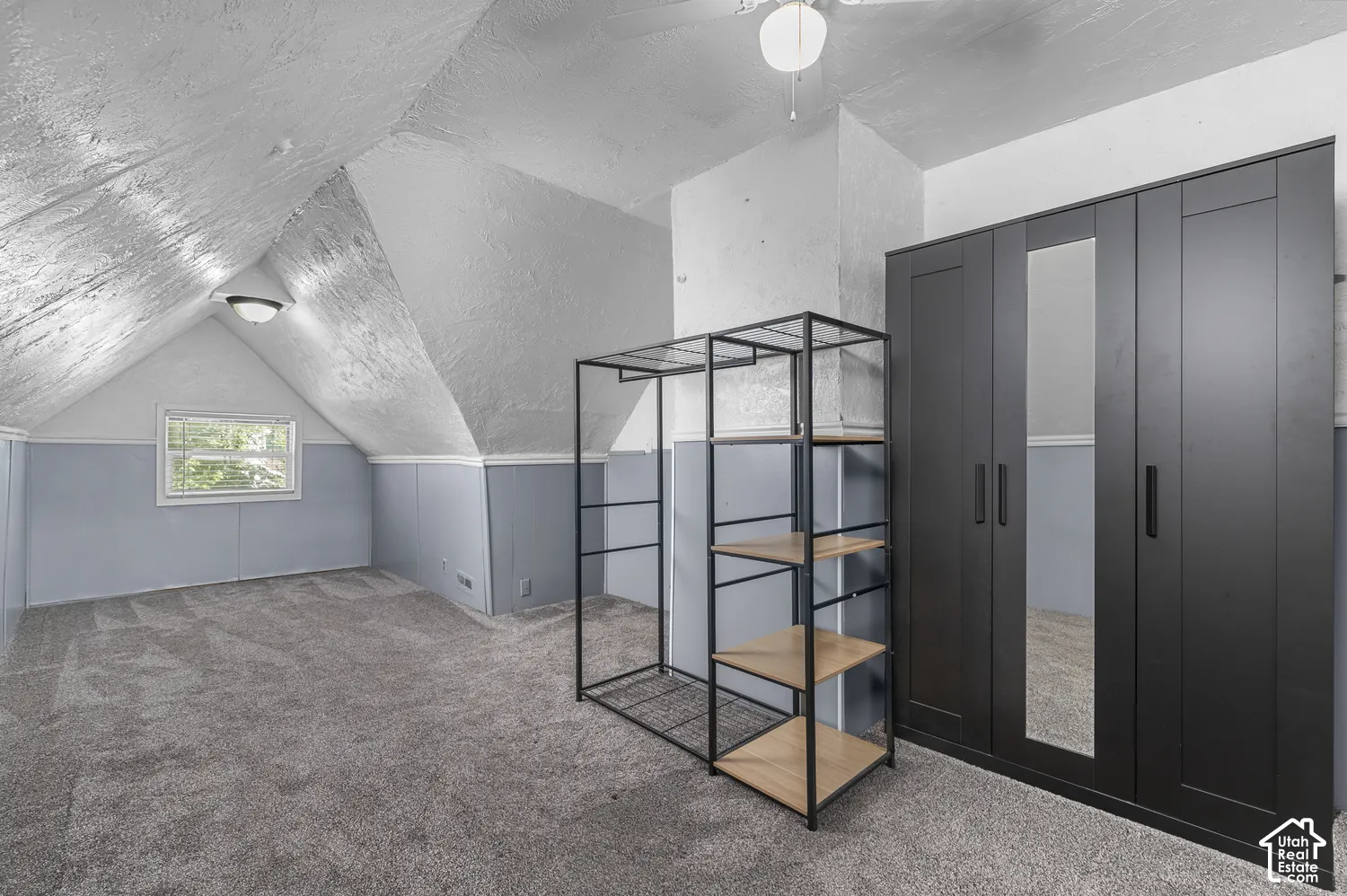 Sloped ceiling with recessed lighting, wall-to-wall carpeting, and a window with natural light