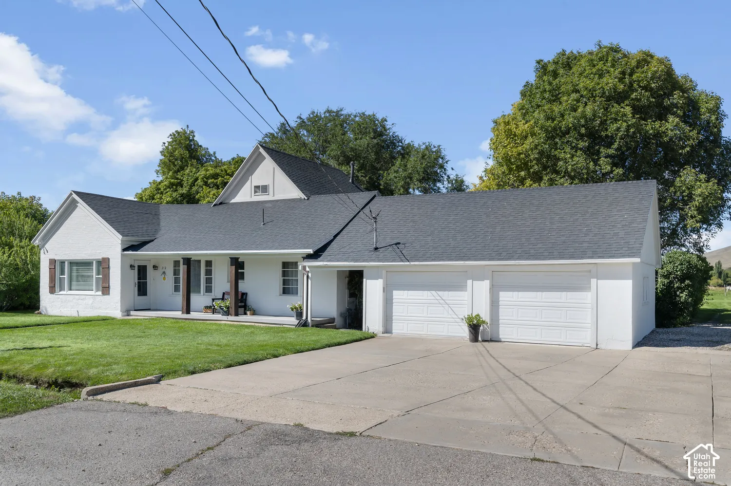 White brick exterior with a dark shingle roof, featuring a covered front porch with dark wood columns