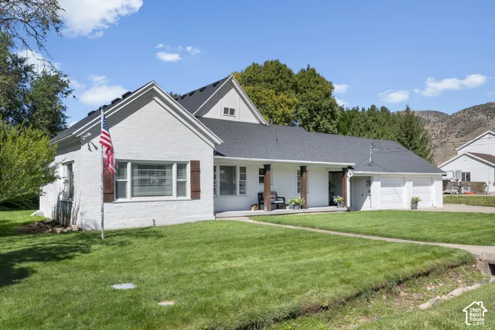 White exterior with dark wood-finish shutters, covered porch, and attached two-car garage