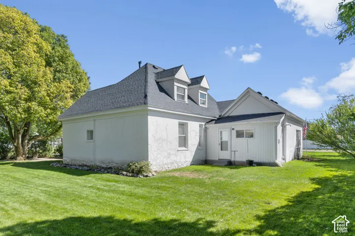 Exterior featuring a stucco facade, dormer windows, a gabled roofline, and a white paneled addition