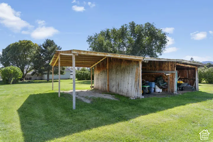 Wooden outbuilding with a corrugated metal roof, providing covered storage and an open carport area