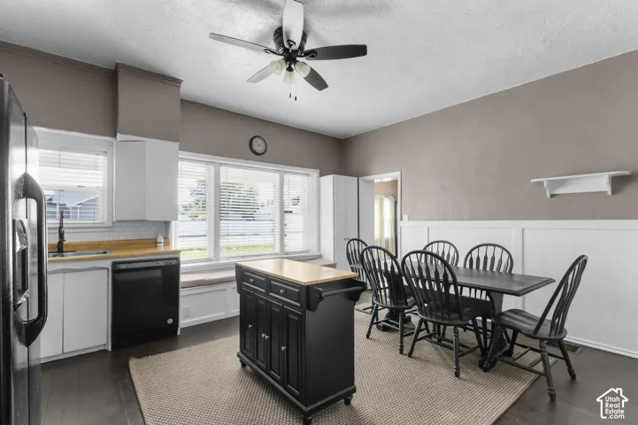 Kitchen and dining area featuring white cabinetry, a white subway tile backsplash, a wood-finish countertop, dark appliances, and a built-in window seat