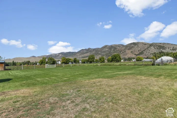 Expansive green space with distant mountain landscape and wood fencing