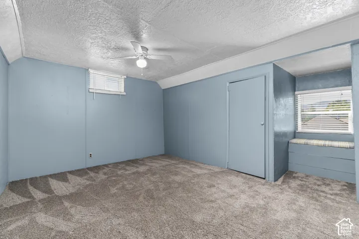 Carpeted room featuring a ceiling fan, a window with blinds, a closet, and a built-in window bench